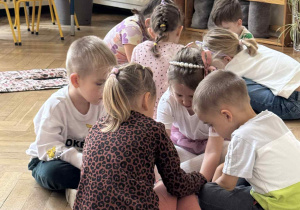 Zdjęcie przedstawia dzieci w kółeczku podczas wykonywania zadania.