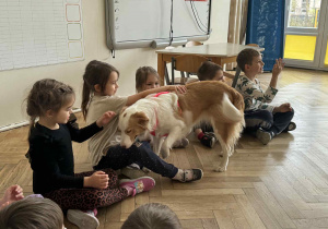 Zdjęcie przedstawia dzieci głaszczące psa.