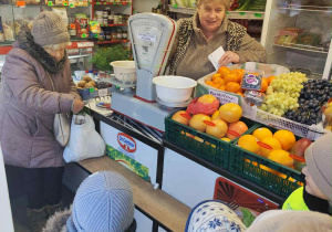 Zdjęcie przedstawia dzieci rozmawiające z panią w sklepie.