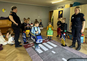 Zdjęcie przedstawia dzieci poruszające się po drodze autkami z gąbki.