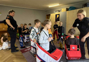 Zdjęcie przedstawia dzieci poruszające się po drodze autkami z gąbki.