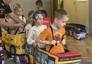 Zdjęcie przedstawia dzieci poruszające się po drodze autkami z gąbki.