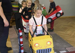 Zdjęcie przedstawia dzieci poruszające się po drodze autkami z gąbki.