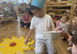 Zdjęcie przedstawia chłopca rozkładającego koraliki na talerzykach słoneczka urodzinowego.