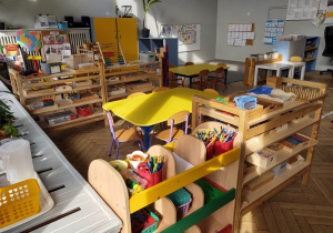 na zdjęciu widać salę przedszkolną grupy pierwszej, stoliki z żółtymi blatami,niskie regały z materiałem rozwojowym dla dzieci