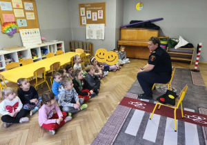 Na zdjęciu widzimy grupkę dzieci które słuchają Pań ze Straży Miejskiej.