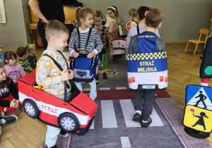 Na zdjęciu widzimy dzieci w autach, którzy "jadą" po drodze.