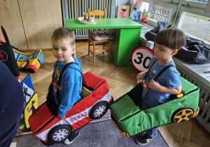 Na zdjęciu widzimy dwójkę chłopców w autach, którzy "jadą" po drodze.