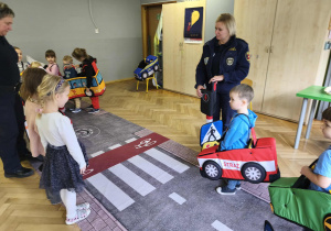 Na zdjęciu widzimy grupkę dzieci w autach i dwie dziewczynki jako piesze, którze przechodzą na pasach.