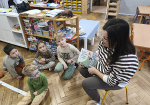 Na zdjęciu widzimy mamę Kubusia i dzieci, które słuchają opowiadania "Ence-pence...".
