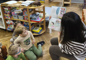 Na zdjęciu widzimy mamę Kubusia i dzieci, które słuchają opowiadania "Ence-pence...".