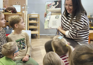 Na zdjęciu widzimy mamę Kubusia i dzieci, które słuchają opowiadania "Ence-pence...".