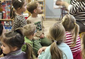 Na zdjęciu widzimy mamę Kubusia i dzieci, które słuchają opowiadania "Ence-pence...".