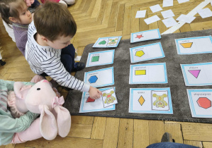 Na zdjęciu widzimy dziecko, które dopasowuje ilustrację misia do jego kształtu na brzuchu.