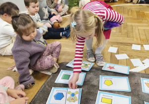 Na zdjęciu widzimy dziecko, które dopasowuje ilustrację misia do jego kształtu na brzuchu.