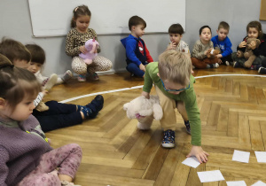 Na zdjęciu widzimy dziecko, które dopasowuje ilustrację misia do jego kształtu na brzuchu.