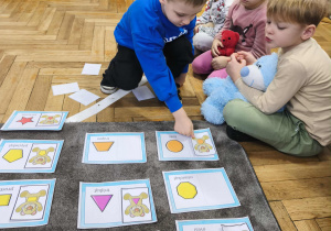 Na zdjęciu widzimy dziecko, które dopasowuje ilustrację misia do jego kształtu na brzuchu.
