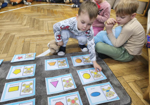 Na zdjęciu widzimy dziecko, które dopasowuje ilustrację misia do jego kształtu na brzuchu.