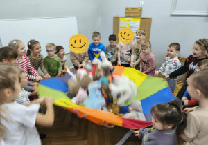 Na zdjęciu widzimy dzieci, które uczestniczą w zabawie z wykorzystaniem chusty animacyjnej.