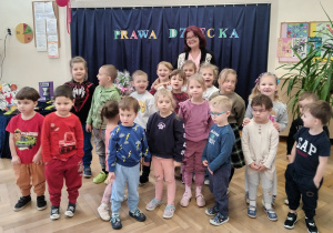 Dzieci stoją wokoło poetki.