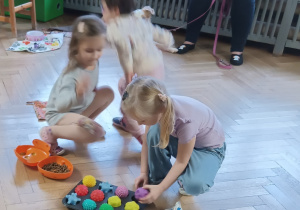 Dzieci ukrywają karmę dla psa pod piłeczkami.