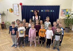 Zdjęcie przedstawia kobietę stojącą razem z dziećmi.