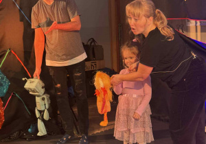 Zdjęcie przedstawia dziewczynkę trzymającą kukiełkę w ręku.