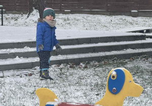 Zdjęcie przedstawia chłopca stojącego na śniegu.