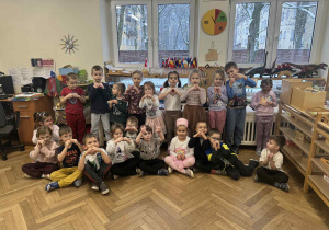 Zdjęcie przedstawia dzieci ustawione w grupie. dzieci robią serduszka z rączek.