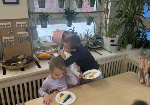 Zdjęcie przedstawia chłopca przytulającego dziewczynkę, podczas składania życzeń.