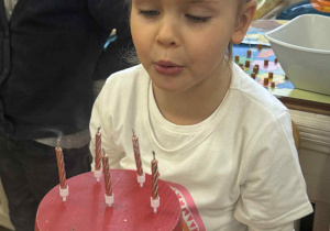 Zdjęcie przedstawia dziewczynkę dmuchającą świeczki.