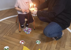 Chłopiec zdmuchuje świeczki na symbolicznym torcie.