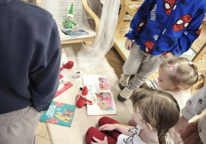 Dzieci obserwują efekt zabaw psotnych Elfów podczas czytania książek