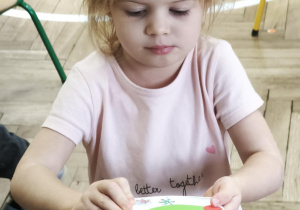 Dziecko pokazuje otrzymaną od kolegi świąteczną kartkę