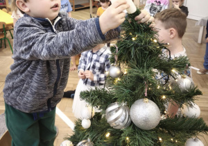 Chłopiec umieszcza gwiazdę na czubku drzewka