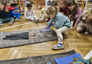 Na zdjęciu widzimy dziewczynkę, która ubiera niewidzialnego Tadka w skarpety.