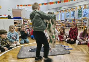 Na zdjęciu widzimy chłopca, który ubiera niewidzialnego Tadka w spodnie dresowe.