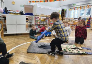 Na zdjęciu widzimy chłopca, który ubiera niewidzialnego Tadka w bluzkę z krótkim rękawem.