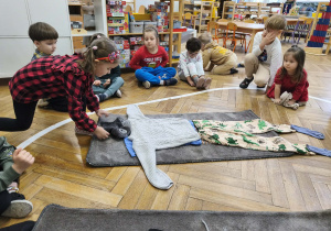 Na zdjęciu widzimy dziewczynkę, która ubiera niewidzialnego Tadka w komin na szyję.