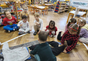 Na zdjęciu widzimy chłopca, który ubiera niewidzialnego Tadka w spodnie narciarskie.