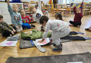 Na zdjęciu widzimy dziewczynkę, która dopasowuje ilustrację swetra do ubioru.