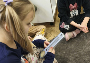 Na zdjęciu widzimy dziewczynkę, która ogląda termometr zaokienny.