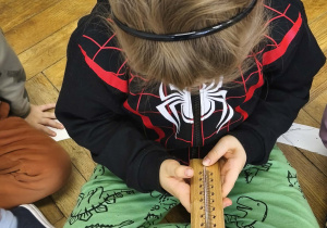 Na zdjęciu widzimy chłopca, który ogląda termometr pokojowy.