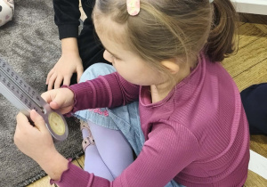 Na zdjęciu widzimy dziewczynkę, która ogląda termometr zaokienny.