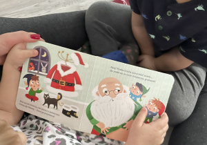 Na zdjęciu widzimy chłopca i dziewczynkę, którzy słuchają czytanej bajki świątecznej.
