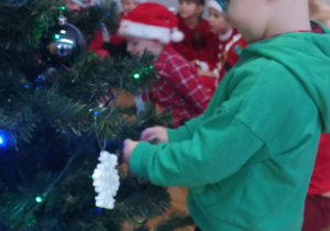 Chłopiec zawiesza ozdobę na choince.