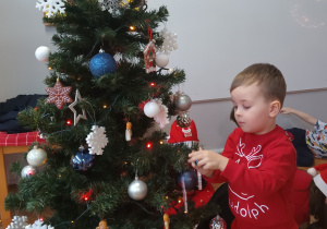 Chłopiec zawiesza ozdobę na choince.