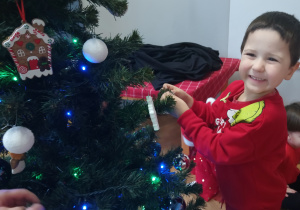 Chłopiec zawiesza ozdobę na choince.