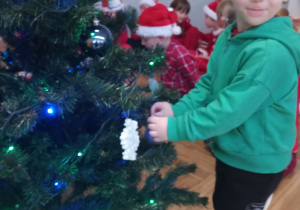 Chłopiec zawiesza ozdobę na choince.