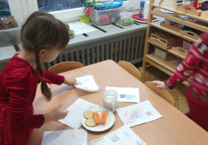 Dziewczynka kładzie list do Mikołaja na stole.